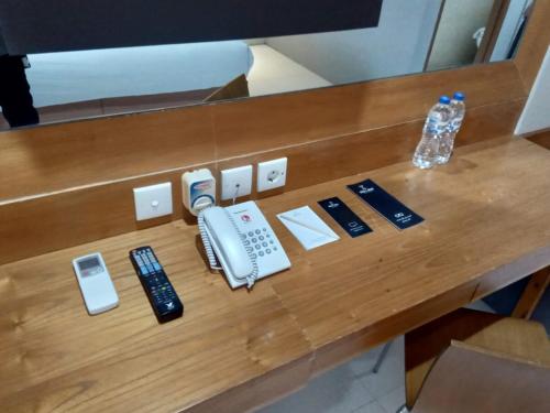 a wooden desk with a phone and other electronics on it at Nite & Day MDC Puncak - Gadog in Bogor