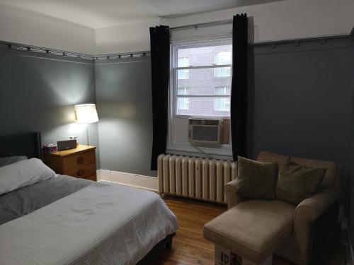 1 dormitorio con 1 cama, 1 silla y 1 ventana en Room with King Bed in Shared 3 Bedroom Downtown, en Montreal