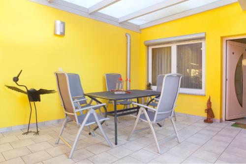 a dining room with yellow walls and a table and chairs at Ferienwohnungen Abendsonne - 8 Gehminuten zum EP in Rust