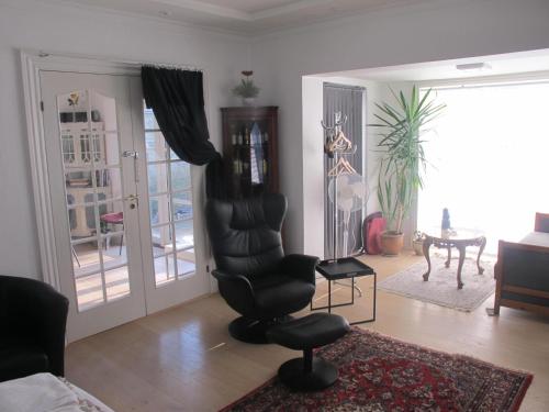 a living room with a black chair and a table at Guesthouse Sharon Apartments in Aarhus