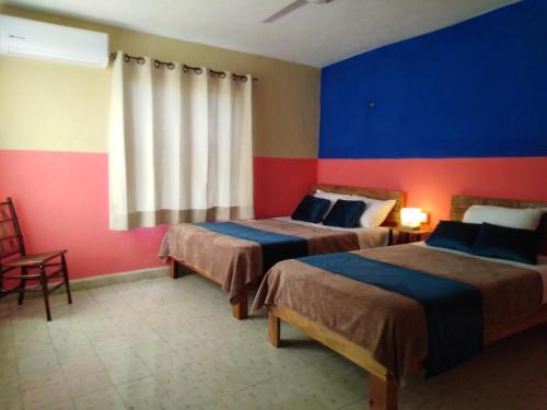 two beds in a room with red and blue walls at Casa Lool Beh in Mérida