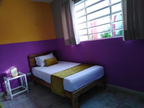 a bedroom with a bed with a purple wall at Casa Lool Beh in Mérida