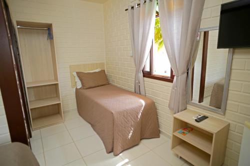 a small room with a bed and a window at Pousada Magnus in Balneário Camboriú