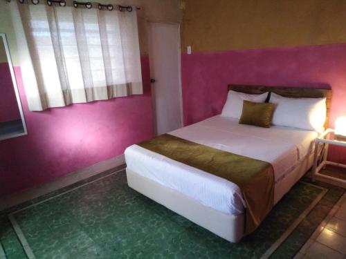 a bedroom with a large bed with a pink wall at Casa Lool Beh in Mérida