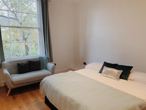 a bedroom with a bed and a chair and a window at SIAC Hampstead Heath Regents Park in London