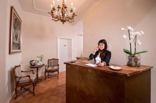 una mujer hablando por un celular en un mostrador en Residenza I Rioni Guesthouse, en Roma