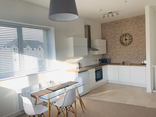 a kitchen with white cabinets and a table and chairs at Ferry House in Pembroke Dock