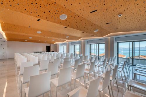 an empty room with white chairs and windows at LAS HOTEL & SPA in Gythio