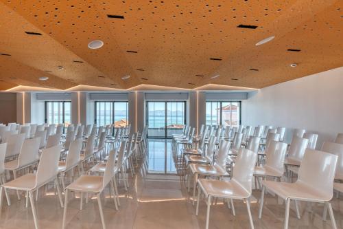 an empty room with white chairs and windows at LAS HOTEL & SPA in Gythio