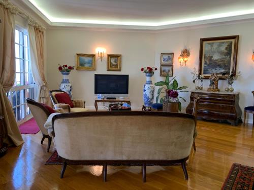a living room with a couch and a tv at Vila Tagus Garajau in Caniço