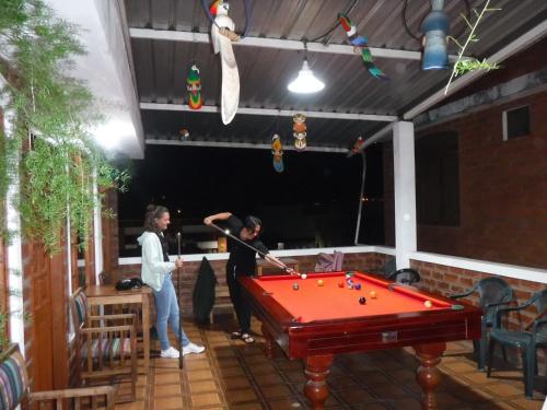 2 personen biljarten op een patio met een pooltafel bij Hostal D´Mathias in Baños