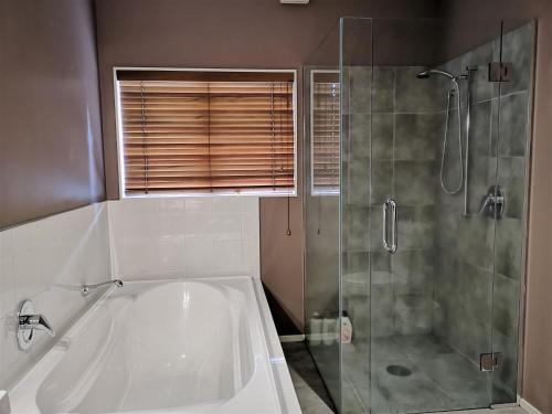 a bathroom with a tub and a glass shower at Lake Taupo Holiday Home in Taupo