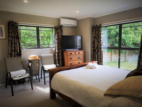 a bedroom with a bed and a flat screen tv at Lake Taupo Holiday Home in Taupo
