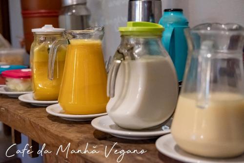 カンブリにあるCasa Bacarirá - Floresta com Yoga e Café da Manhã Veganoのテーブルの上に牛乳とオレンジジュースの入ったガラス容器が4つある