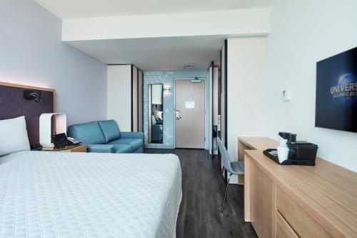 a hotel room with a bed and a desk and a television at Universal's Aventura Hotel in Orlando