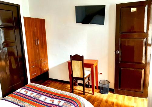 a bedroom with a bed and a table and a chair at Hotel Santa Maria in Cusco