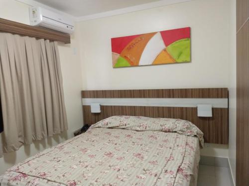 a bedroom with a bed and a painting on the wall at Lacqua diRoma 1 - Apartamentos JN in Caldas Novas