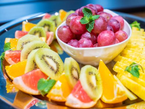 a plate of fruit with a bowl of grapes and kiwis at APA Hotel & Resort Midosuji Hommachi Eki Tower in Osaka