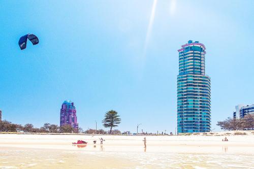 uma pessoa a lançar um papagaio numa praia com edifícios altos em The Waterford on Main Beach em Gold Coast
