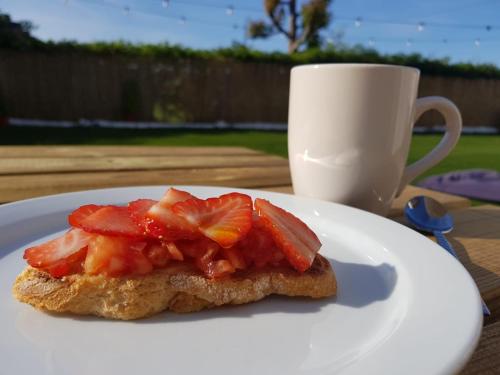 a piece of bread with strawberries on a plate with a cup at La Casita de Melón in Suances