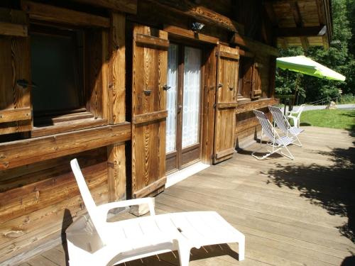 eine Veranda einer Holzhütte mit Stühlen und einem Sonnenschirm in der Unterkunft Peaceful Chalet in Les Houches with Mountain Views in Les Houches