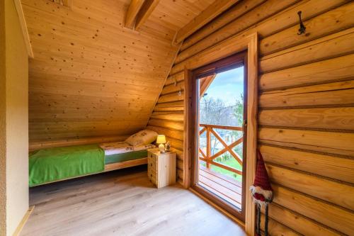 Habitación con cama y ventana en una cabaña de madera en DOMKI SWOJSKIE CHATKI, en Szczytna