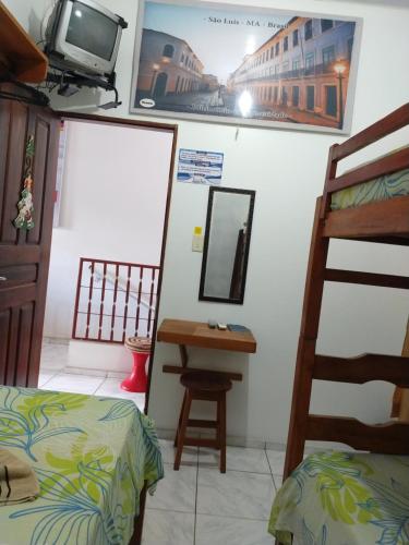 a room with a bed and a desk and a television at Pousada Jatobá in Barreirinhas