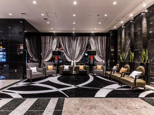 a lobby with couches and chairs on a rug at APA Hotel & Resort Midosuji Hommachi Eki Tower in Osaka