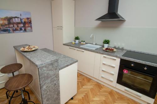uma cozinha com armários brancos e um balcão com bancos em Vracar Vuk 2 em Belgrado
