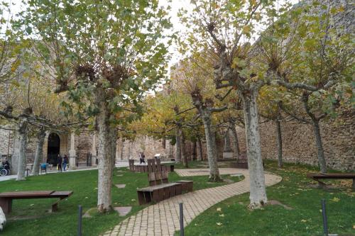a park with benches and trees in front of a building at Puente Viejo de Buitrago CASA ROBLE in Buitrago del Lozoya