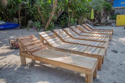 a row of wooden benches sitting on the beach at Lae Tawan Bungalow in Koh Chang Ranong