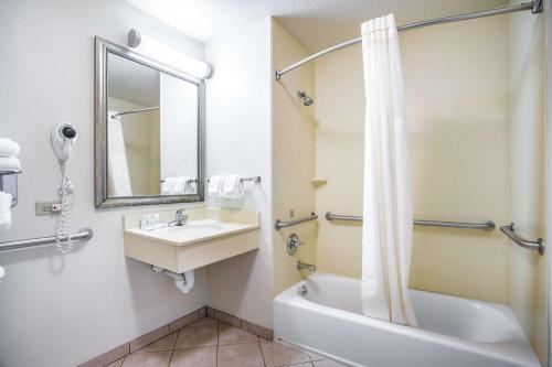 Quality Inn في Parsons: حمام مع حوض وحوض استحمام ومرحاض