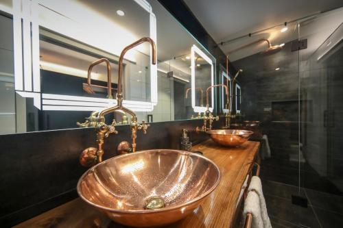 a bathroom with a copper sink and mirrors at L'amour Nest in Napier