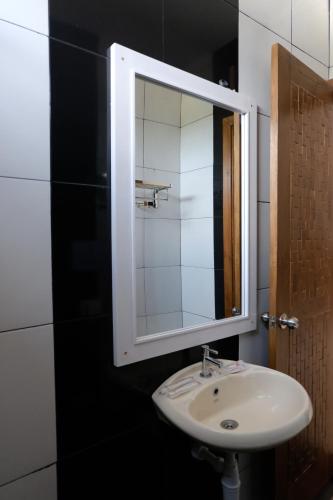 ein Badezimmer mit einem weißen Waschbecken und einem Spiegel in der Unterkunft Baratha Hotel & Resto in Bondowoso