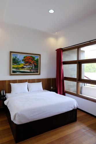 a bedroom with a large white bed and a window at Baratha Hotel & Resto in Bondowoso