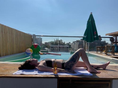 uma mulher deitada numa mesa em frente a uma piscina em Straw Hat Hostel & Rooftop Bar em Tulum