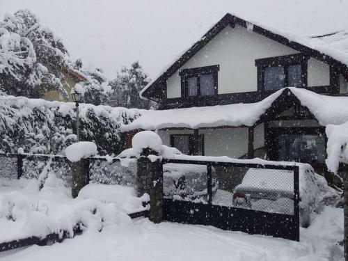 a house covered in snow in front at Las Rosas Alojamiento Turistico in Villa La Angostura