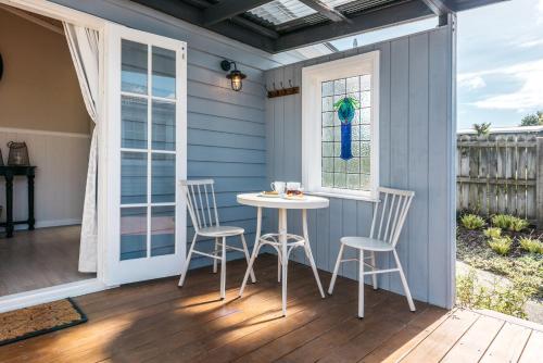 a patio with a table and chairs on a deck at Pohutukawa Cottage, Waiheke Island in Surfdale