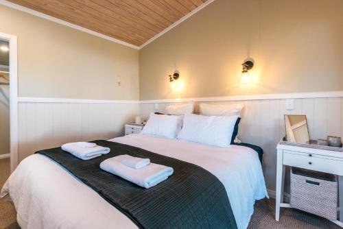 a bedroom with a bed with two towels on it at Pohutukawa Cottage, Waiheke Island in Surfdale