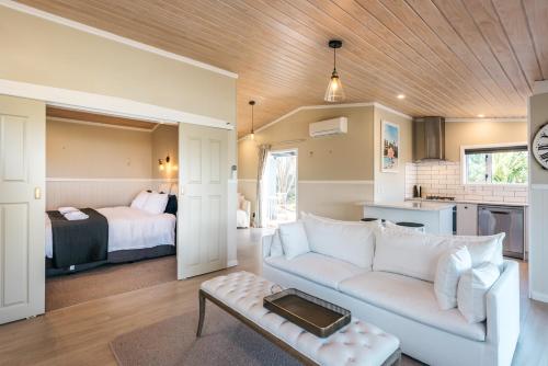 a living room with a couch and a bedroom at Pohutukawa Cottage, Waiheke Island in Oneroa