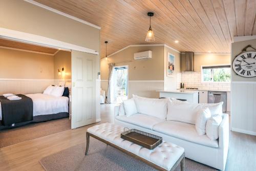 a living room with a couch and a bedroom at Pohutukawa Cottage, Waiheke Island in Surfdale