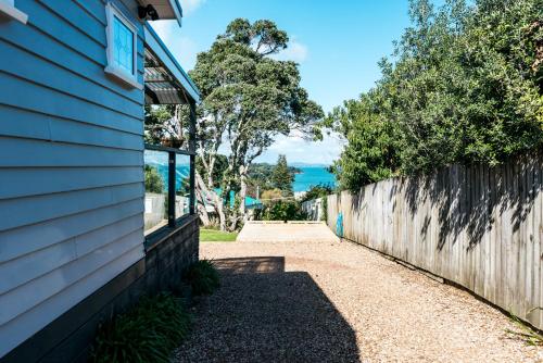 a walkway next to a house with a fence at Pohutukawa Cottage, Waiheke Island in Surfdale