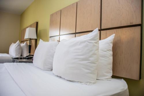 a bed with white pillows in a hotel room at Candlewood Suites Overland Park W 135th St by IHG in Overland Park