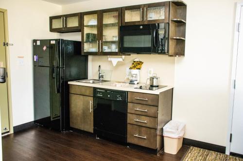 a kitchen with a black refrigerator and a sink at Candlewood Suites Overland Park W 135th St by IHG in Overland Park