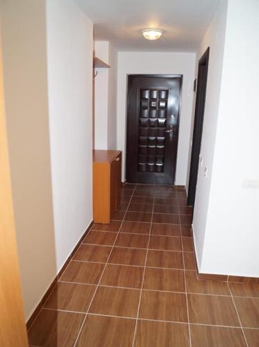 a hallway with a black door and a brown tile floor at Militari Residence Studio in Roşu