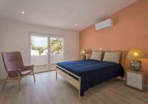 a bedroom with a bed and a chair and a window at Vicky Rae Beach House - Vale do Lobo in Almancil