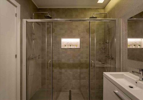 a bathroom with a glass shower with a sink at Vicky Rae Beach House - Vale do Lobo in Almancil