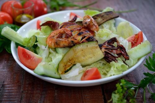 a plate of salad with shrimp and tomatoes on a table at Amami Beachfront Villa with Private Beach in Puerto Galera