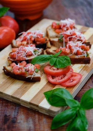 a wooden cutting board with sandwiches with tomatoes and basil at Amami Beachfront Villa with Private Beach in Puerto Galera