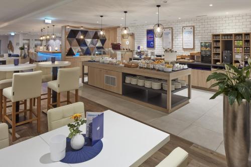 a restaurant with tables and chairs and a cafeteria at Holiday Inn Express - Merzig by IHG in Merzig